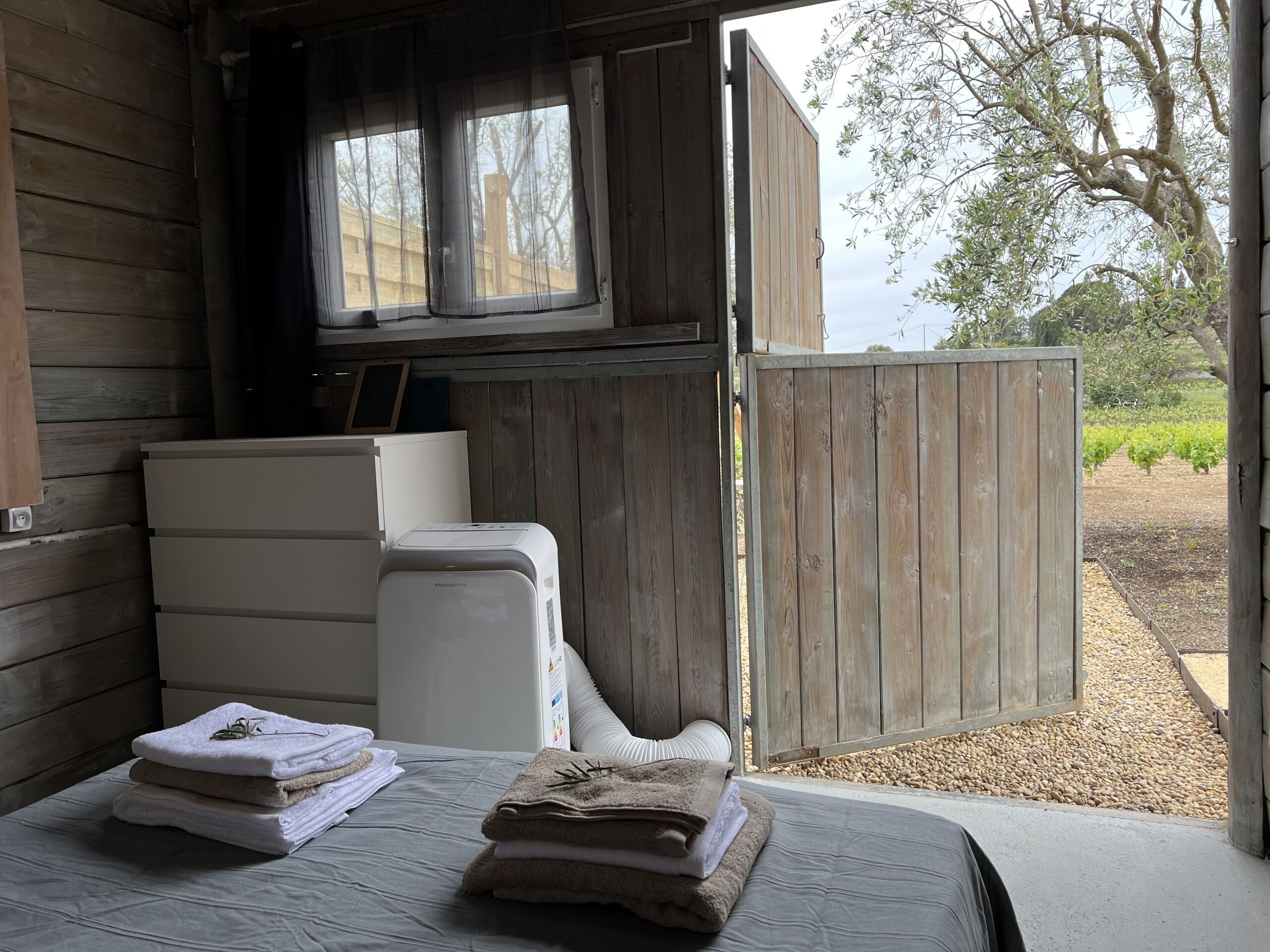 Una habitación con una cama, un calentador blanco y una puerta de madera que da al exterior.