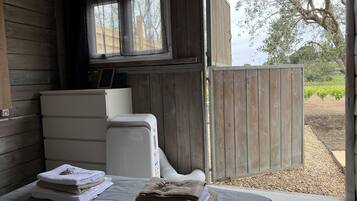 Una habitación con una cama, un calentador blanco y una puerta de madera que da al exterior.