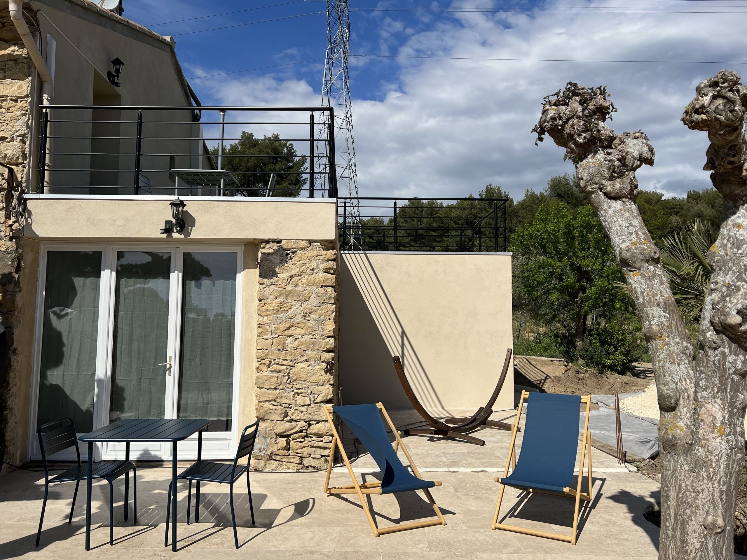 A two-story building with a balcony, stone walls, and a view of the surrounding landscape.