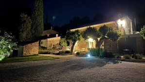 A stone building with a thatched roof, surrounded by greenery and a paved driveway. - Le Mas Golie (Le Castellet)