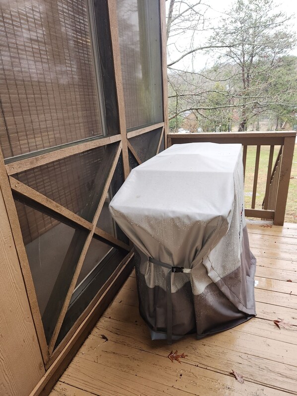 Un espacio de estar al aire libre techado con una mesa cubierta con mantel blanco, un mosquitero y una terraza de madera.
