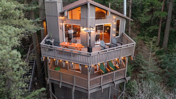 Une cabane en bois à plusieurs niveaux, dotée d’une terrasse, de meubles d’extérieur et d’une cheminée.