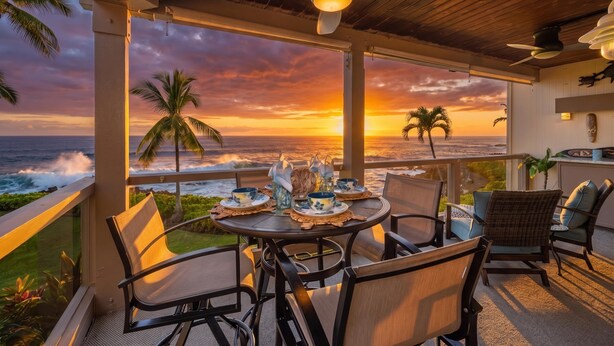 A balcony with a table set for dining, overlooking the ocean at sunset.