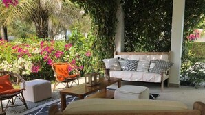 An outdoor seating area with wicker chairs, a wooden table, and a sofa with patterned cushions. - Villa Citronsverts (Cap skirring)