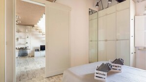 A bedroom with a bed, a wardrobe, and a bathroom visible through an open door. - House Of The Architect - Sweet Apartment (Cesena)