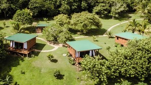 Uma pousada ecológica isolada com cabanas de madeira, cada uma com telhado verde, cercada por vegetação exuberante e árvores.