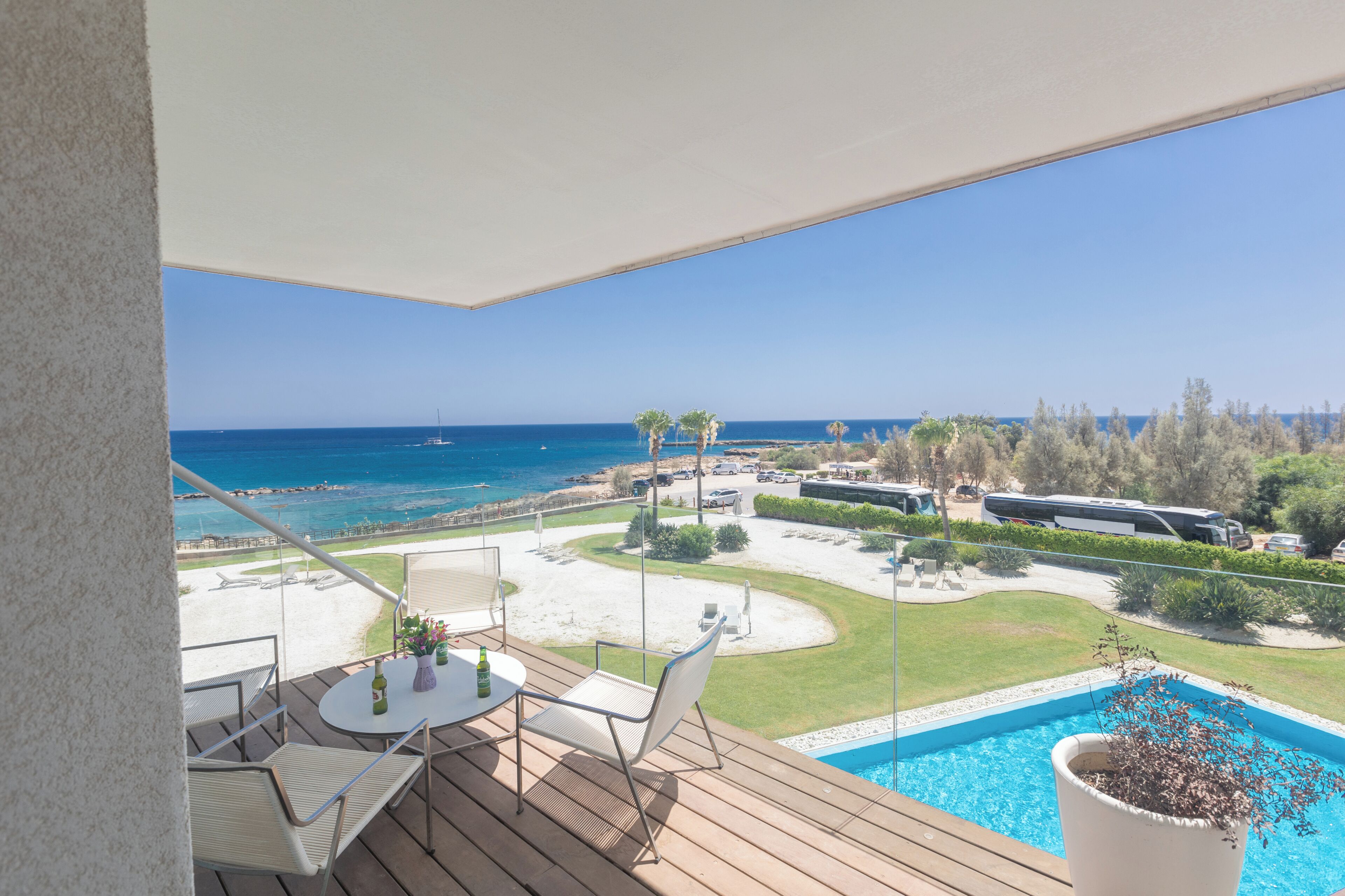 En balkon med pool, udendørs møbler og udsigt til strand og hav.