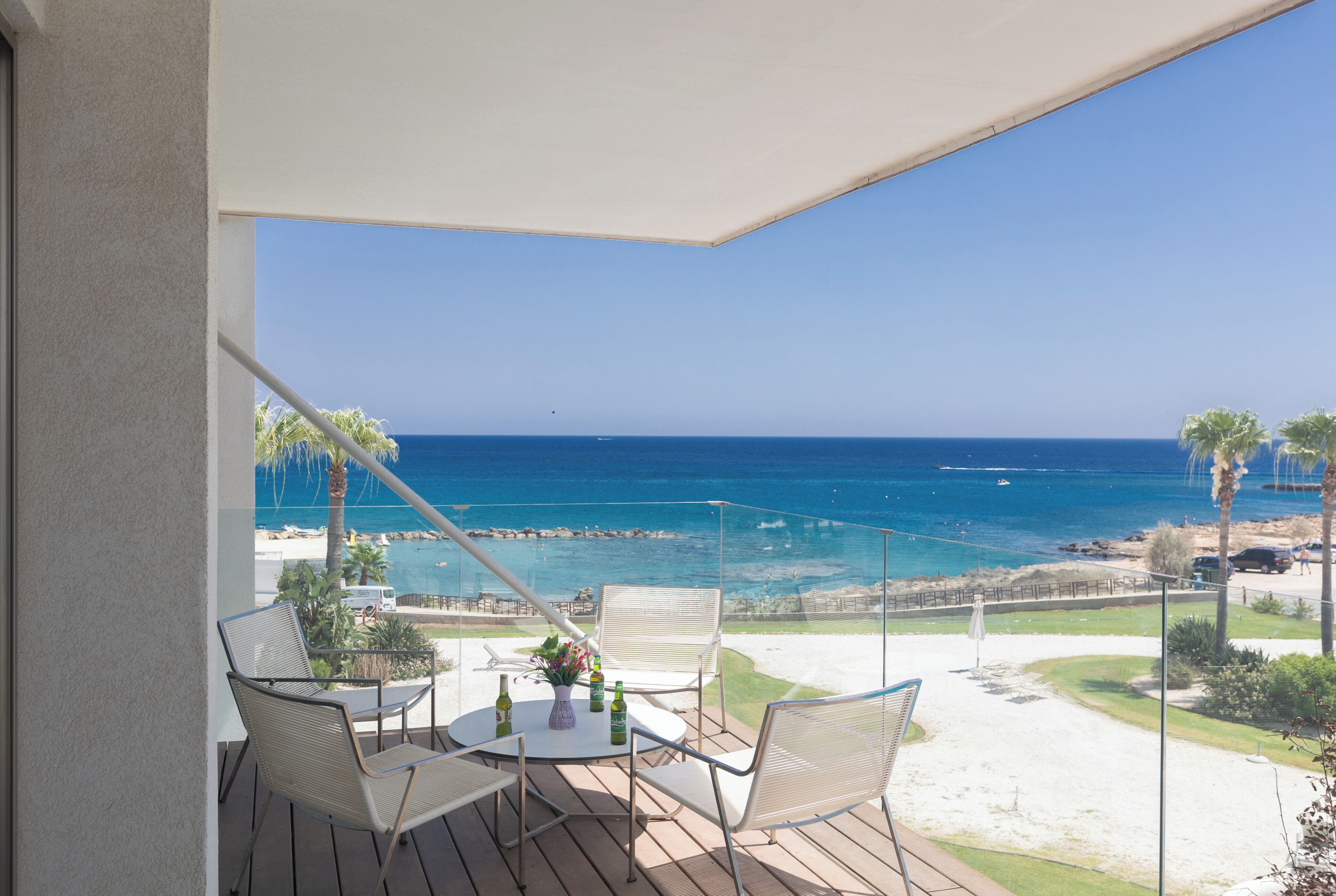 Un balcón con mesa y sillas, con vista a una playa y al océano.
