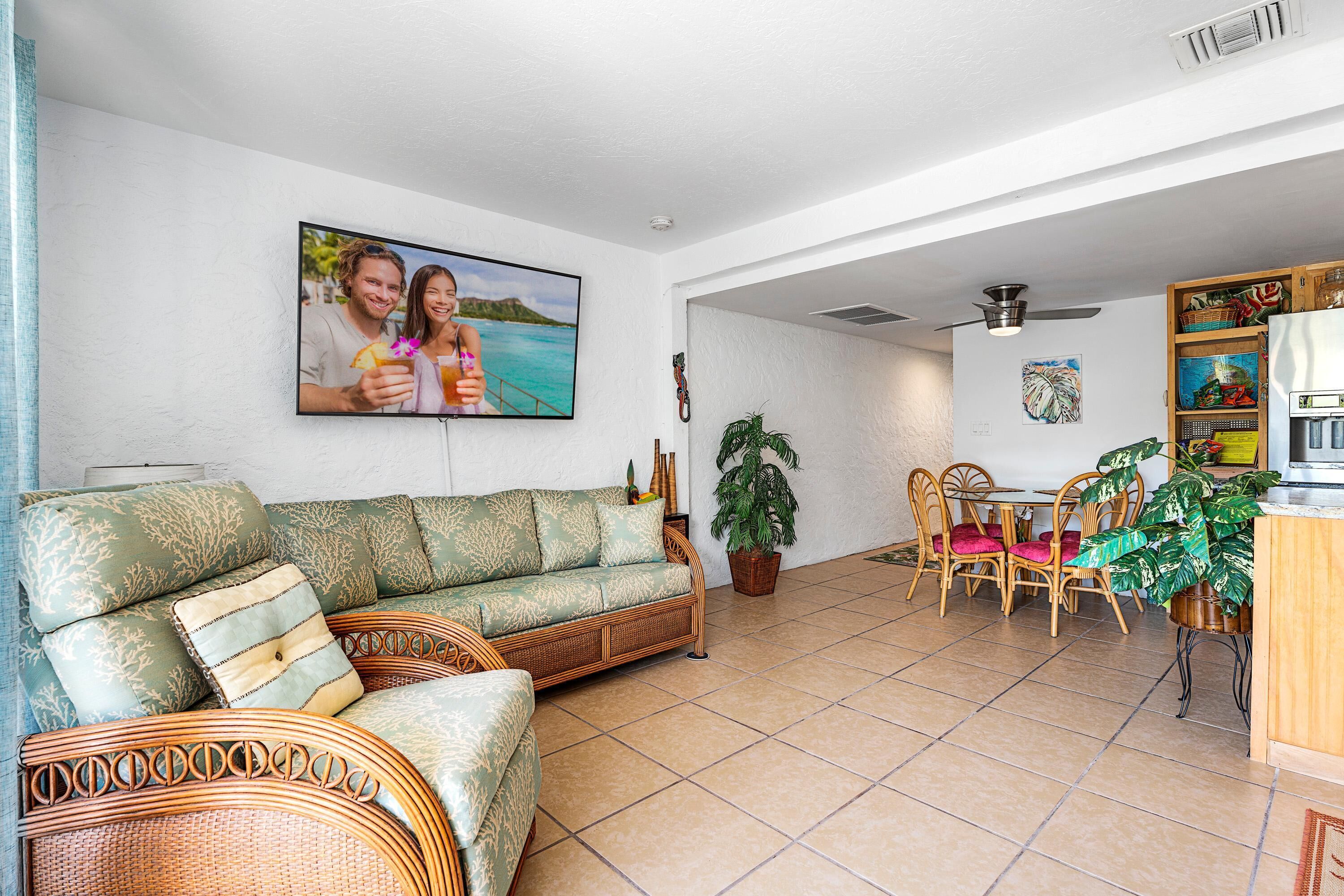 Una sala de estar con sofá, mesa de comedor, sillas y televisor.