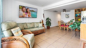 A living room with a sofa, dining table, chairs, and a TV.