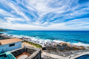 A coastal view with a stone wall, a small building, and a clear blue sky. - Casa De Emdeko 230 (Kailua-Kona)