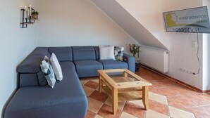 Una sala de estar moderna con un sofá modular, una mesa de centro de madera y piso de baldosas.