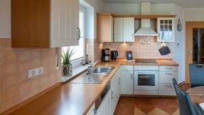 Una cocina compacta con armarios blancos, encimera de madera, horno empotrado y un lavamanos.