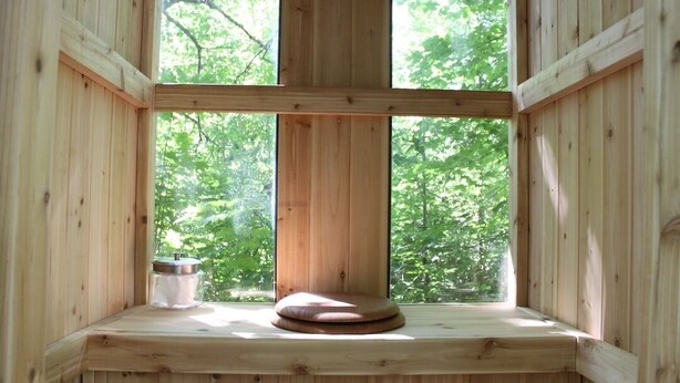 Ein Holzkamin mit Blick auf Bäume, ein hölzerner Hocker und ein Glasbehälter.