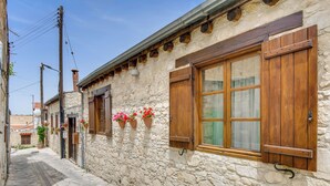 A narrow stone building with wooden shutters and flower boxes. - Sanders Arsorama Comfy 1 Bdr Apt w Shared Patio (Arsos)