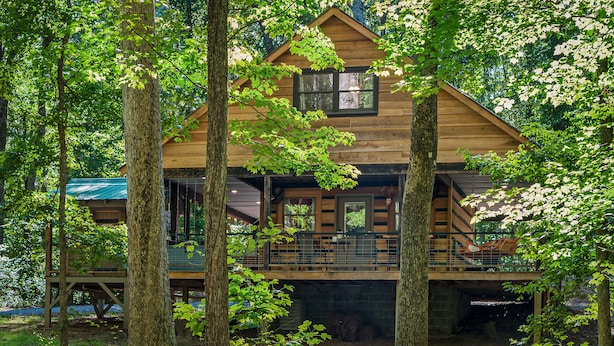 A wooden cabin with a balcony, surrounded by trees.