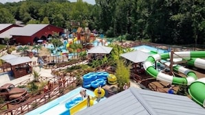 A water park with multiple slides and pools, surrounded by trees and buildings.