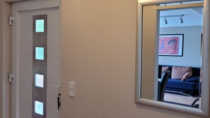 A hallway with a white door, a wall-mounted mirror, and a ceiling light fixture.