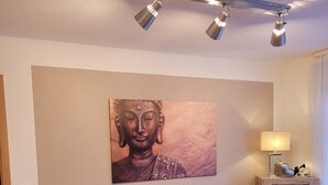 A living room with a blue sofa, a Buddha painting, a lamp, and a cabinet.