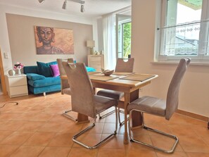 Un comedor con mesa de madera y sillas de metal, sofá azul y un cuadro de Buda en la pared.