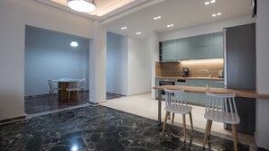 Een moderne keuken met een marmeren vloer, een eethoek met tafel en stoelen, en een bar met krukken.