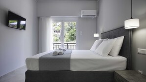 Een moderne hotelkamer met een groot bed, een aan de muur bevestigde televisie, en een balkon met uitzicht op groen.