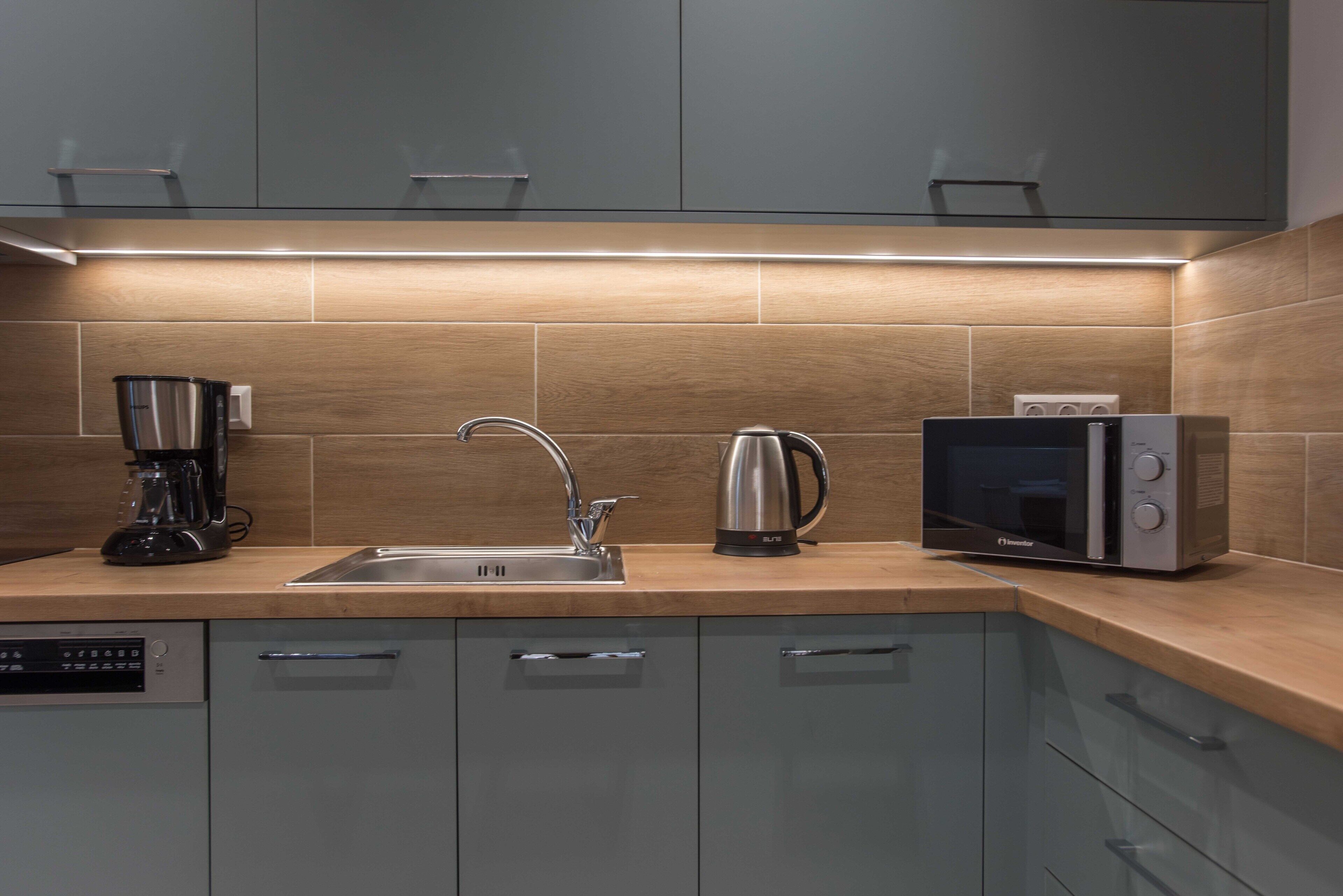 A modern kitchen with a built-in dishwasher, a coffee maker, a kettle, and a microwave.