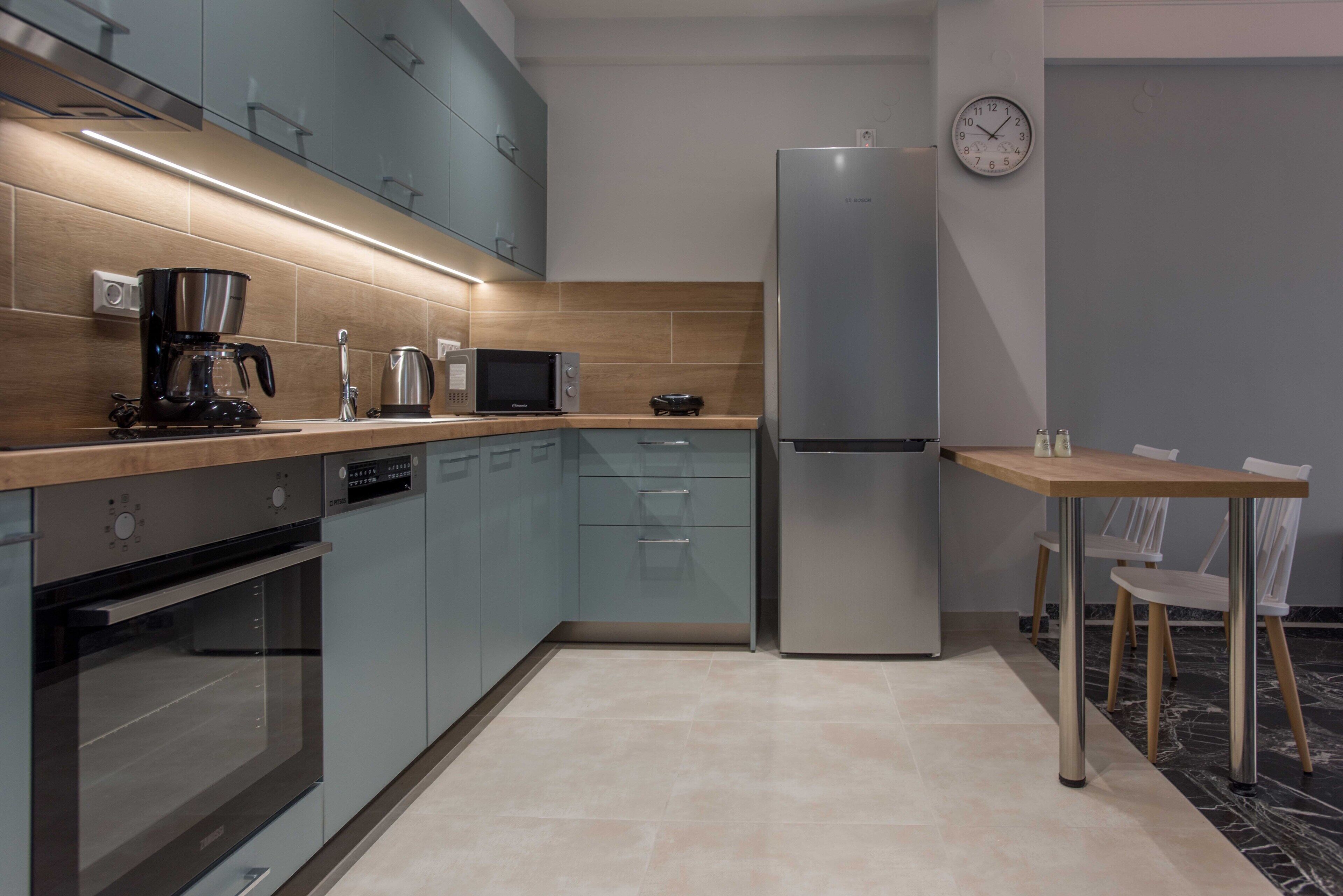 Una cocina moderna con horno integrado, microondas, cafetera y refrigerador.