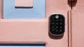 A keypad door lock mounted on a wall with a blue and pink color scheme.