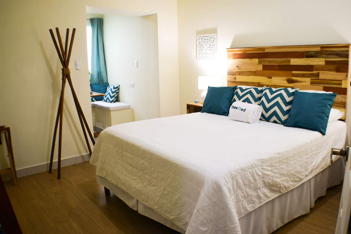 A neatly made bed with a wooden headboard, a bedside table, and a lamp.
