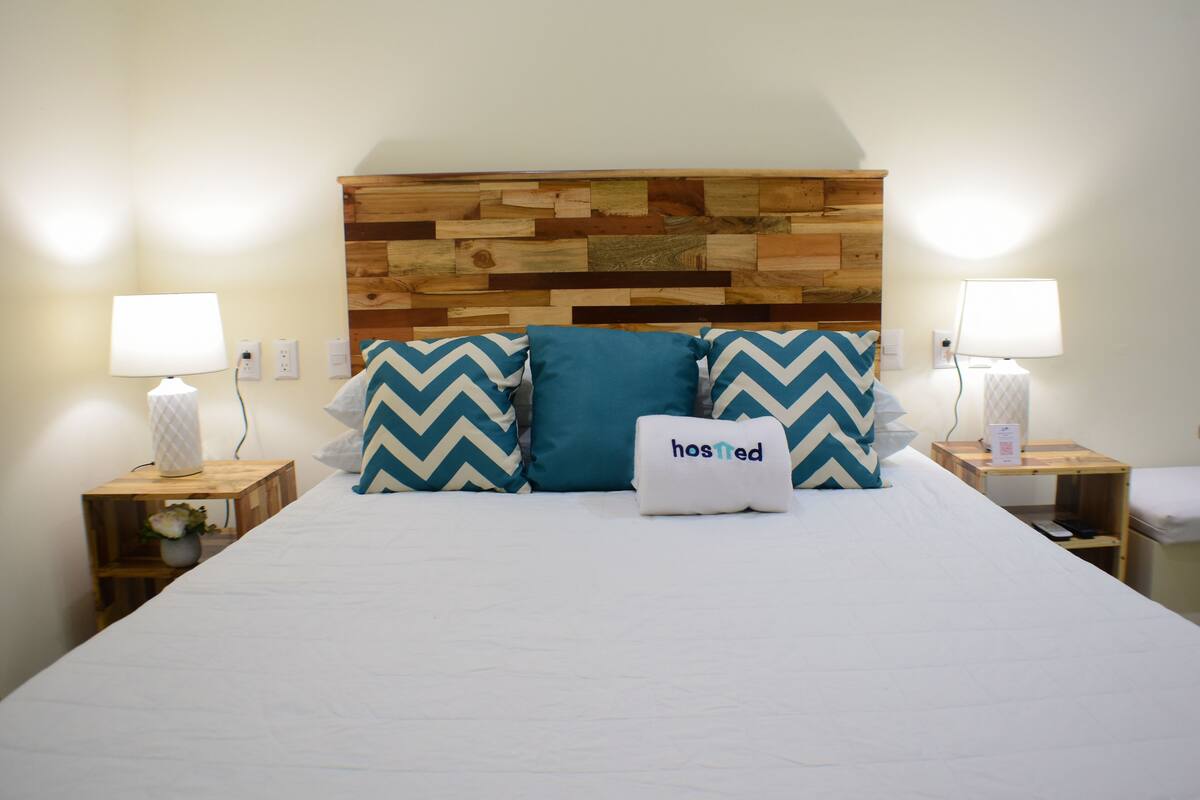 A neatly made bed with a wooden headboard, two bedside lamps, and decorative pillows.