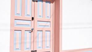 A double door with a pink and blue color scheme, set in a white building with a red roof. - Hostted (Flores)