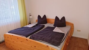 A double bed with a wooden frame, two pillows, and a bedside lamp.
