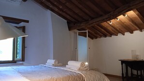 Un dormitorio con una cama grande, techo de madera y una mesita.