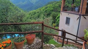 Un edificio rústico con balcón que da a un valle exuberante y montañas.