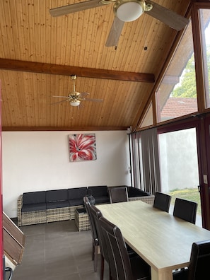 Ein Zimmer mit Holzwänden, einem Esstisch, Stühlen und einem Deckenventilator.