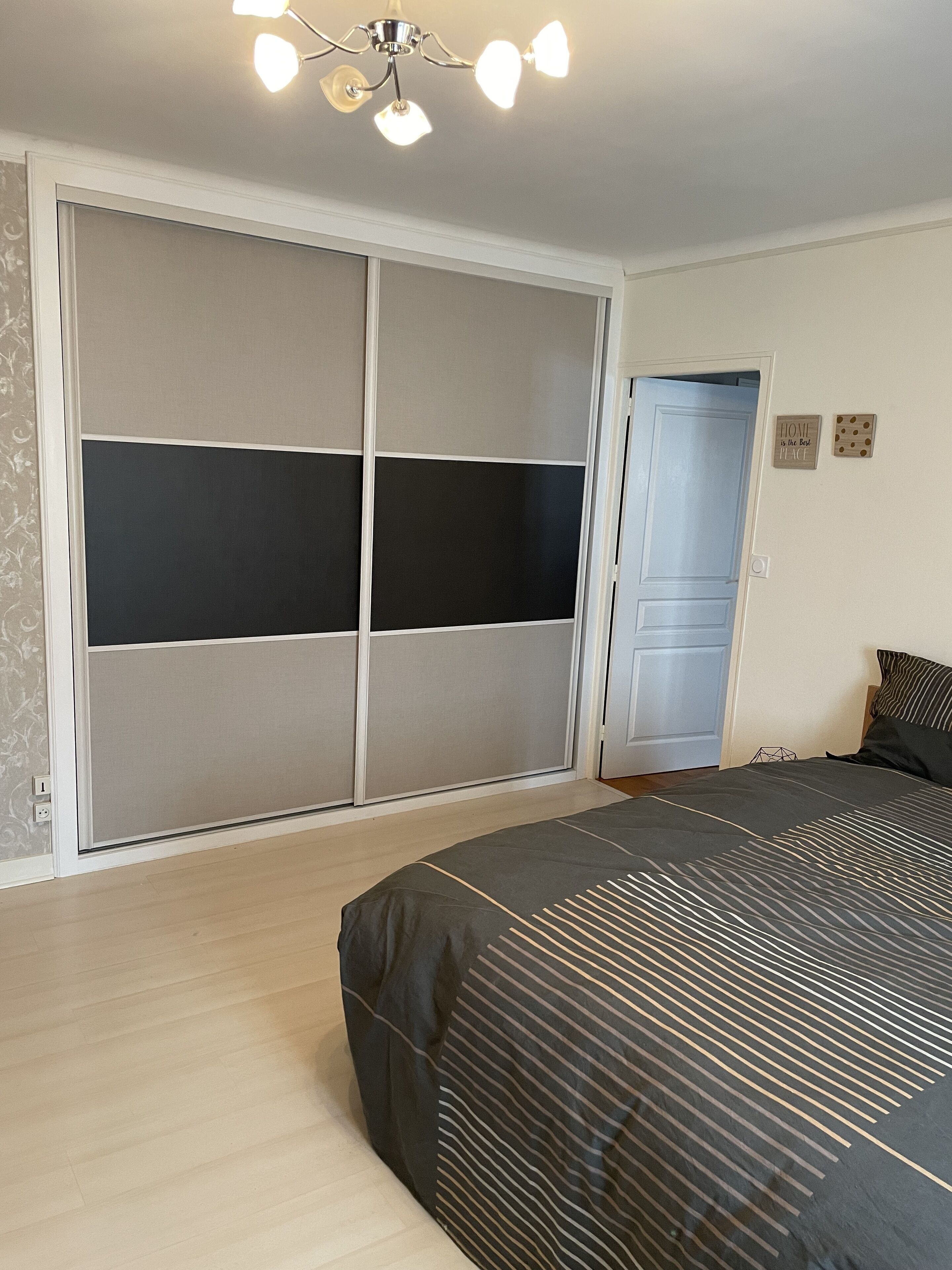 Une chambre à coucher avec un lit, une armoire, un ventilateur de plafond et une porte.