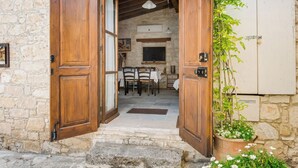 A rustic stone building with a wooden door leading to a dining area with a table and chairs. - Sanders Arsorama - Sweet 1-bdr Apt w/ Shared Patio (Arsos)