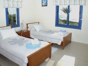 A room with two single beds, a nightstand with a lamp, and a window with a view of the sea. - Sea Front Villa, Heated Private Pool, Amazing Location Paphos 323 (Kissonerga)