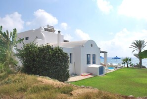 A white building with a pool, surrounded by greenery and a view of the sea. - Sea Front Villa, Heated Private Pool, Amazing Location Paphos 323 (Kissonerga)