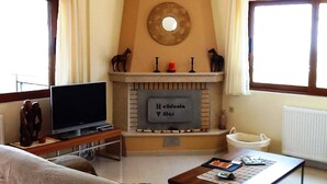 A living room with a fireplace, a television, a coffee table, and a sofa. - Villa Stefanos, Sea View, Private Pool, Near Sea (Rethymno)