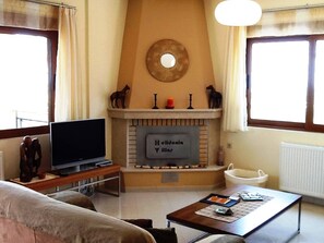 A living room with a fireplace, a television, a coffee table, and a sofa.