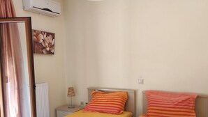 A room with two beds, an air conditioning unit, a lamp, and a window with curtains. - Villa Stefanos, Sea View, Private Pool, Near Sea (Rethymno)