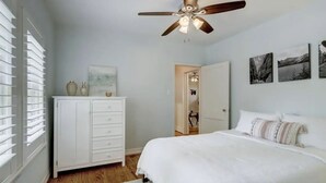 Ein Schlafzimmer mit einem Bett, einem Deckenventilator, einem Schminktisch und einem Kleiderschrank.