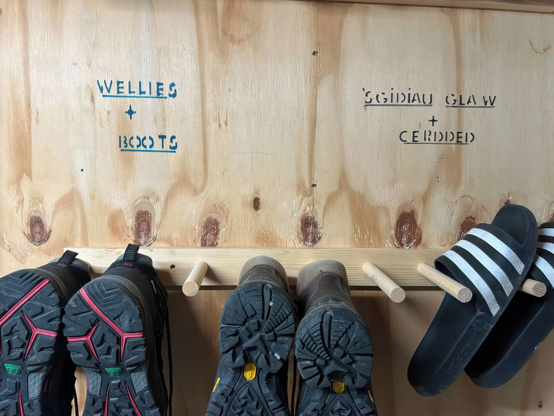 A wooden shoe rack with labels for different types of footwear.