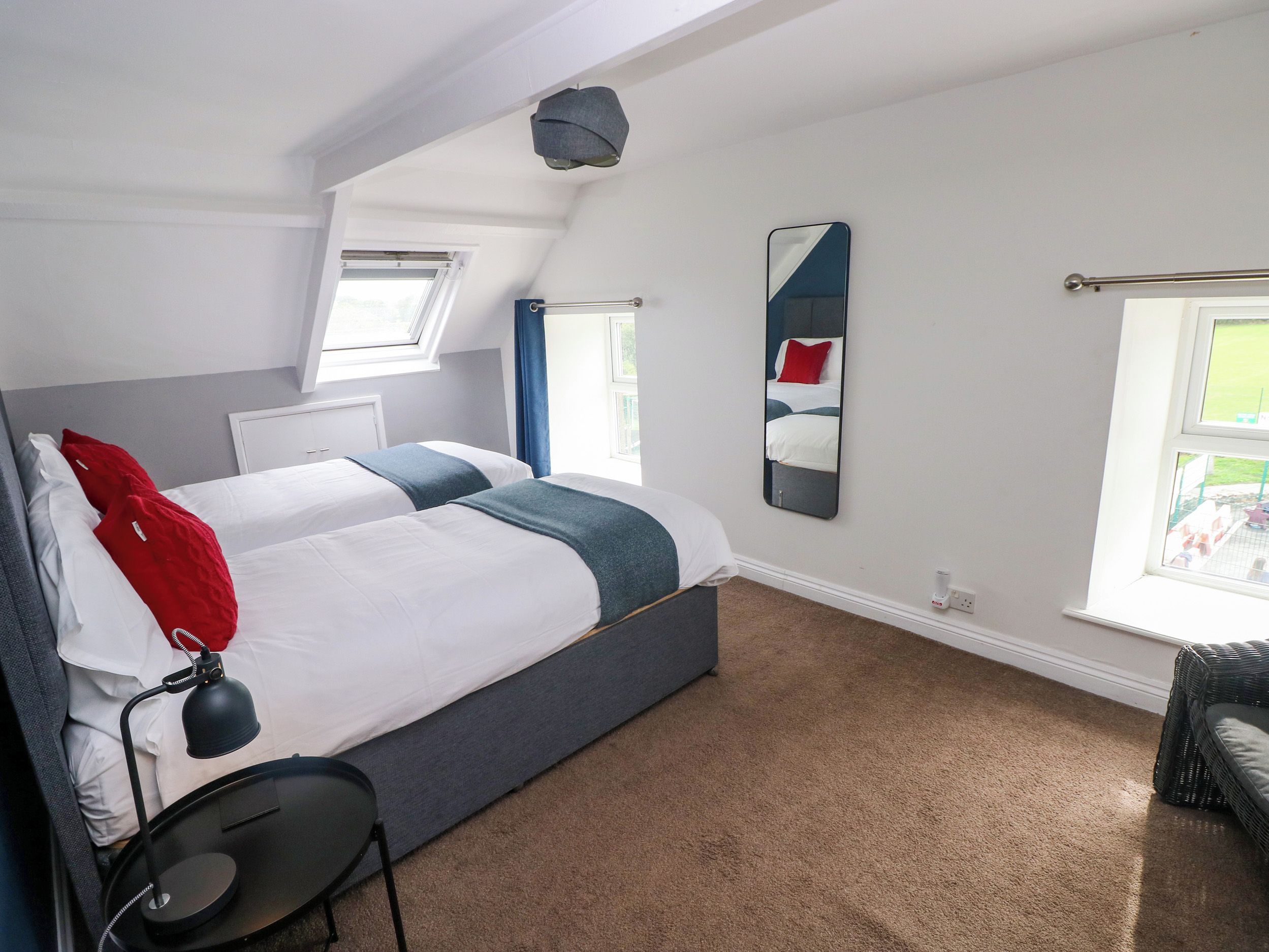 Habitación de hotel con una cama grande, un escritorio, una silla, un espejo y una ventana.