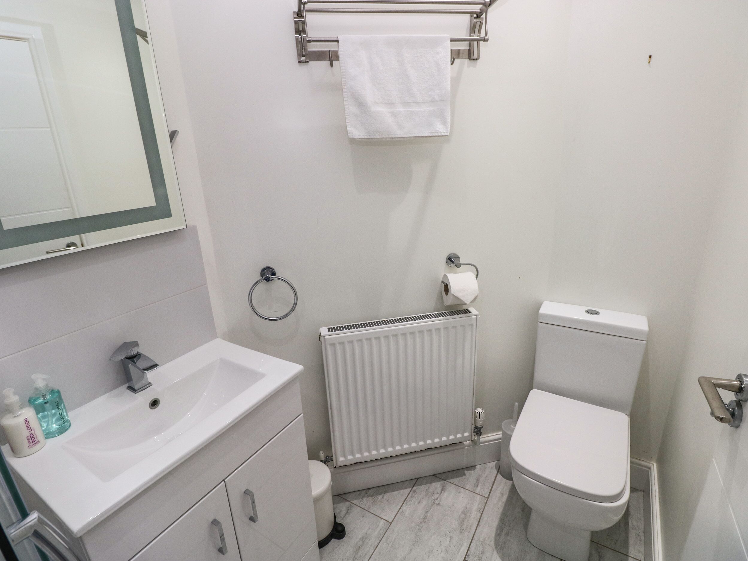 Un baño moderno con lavamanos, inodoro y radiador blancos.