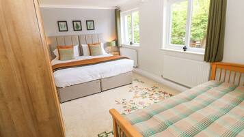 A bedroom with a bed, a dresser, a window with curtains, and a radiator.