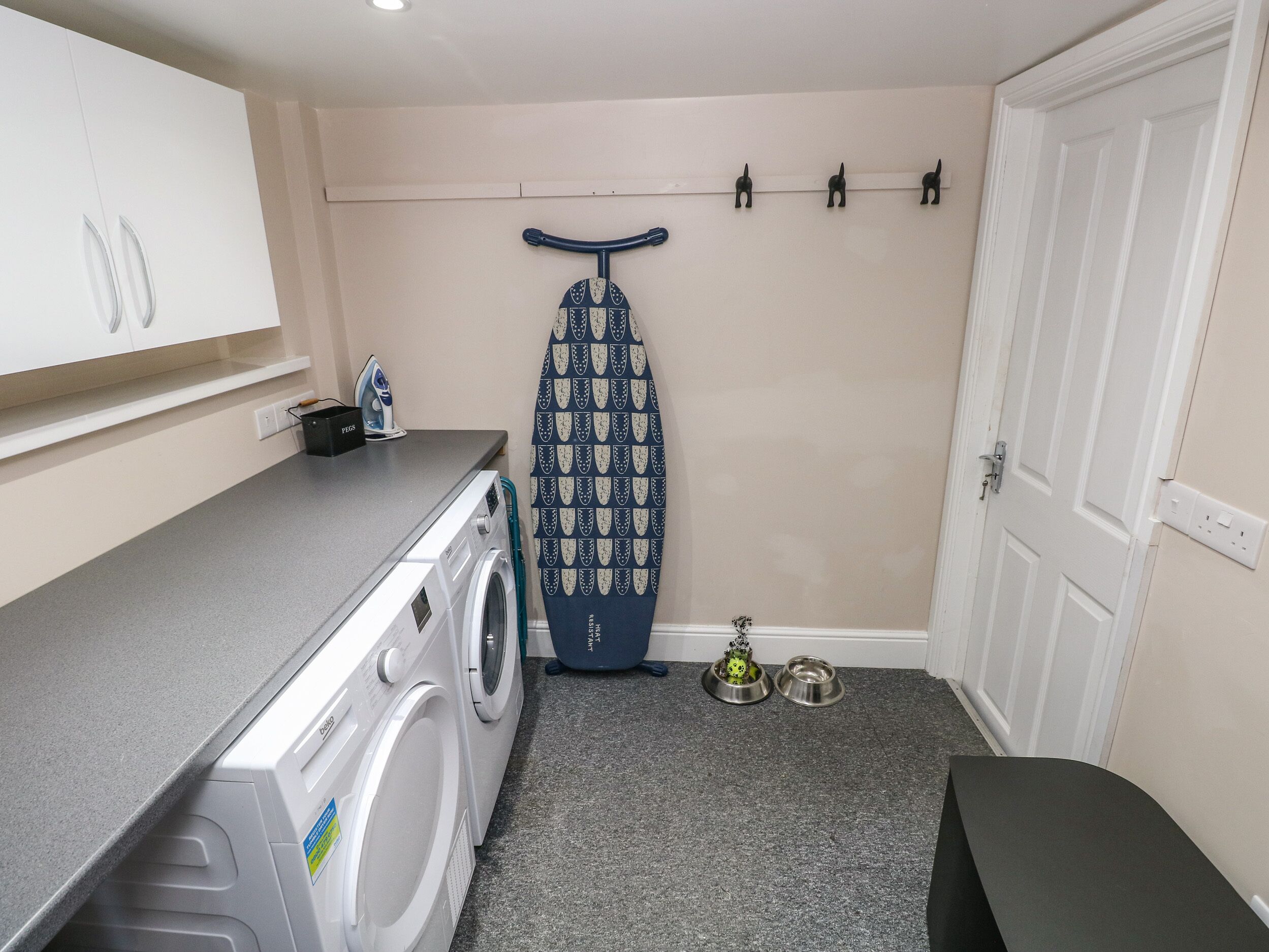 A laundry area with a washing machine, an ironing board, and a drying rack.