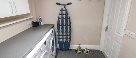 A laundry area with a washing machine, an ironing board, and a drying rack.